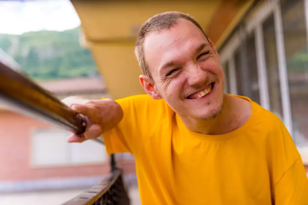 A disabled man wearing a yellow shirt smiling