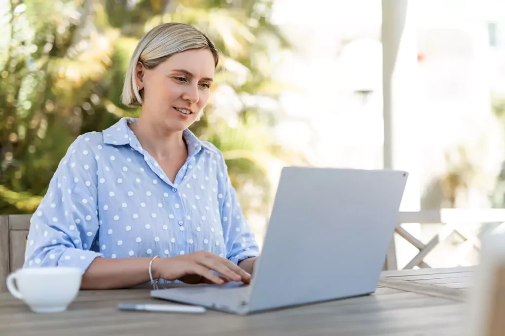 A woman sitting outside looking at her laptop